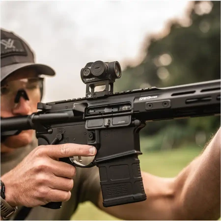 Kolimator karabinowy Vortex Triumph 2 MOA zamontowany na karabinku AR-15 trzymanym w dłoniach przez strzelca.