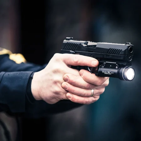 Latarka pistoletowa Streamlight TLR-1 HL zamontowana na broni trzymanej przez użytkownika.