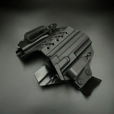 Kabura Glock 19 Doubletap Appendix Elastic IWB z ładownicą na ciemnym tle. Pazur zapewniający dociskanie chwytu pistoletu.