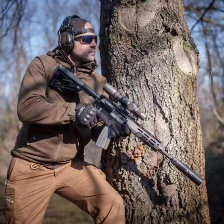 Tłumik Gomander TACTINOX QD-LOCK L 5.56 mm na karabinku AR15 z zamontowaną lunetą biegową.